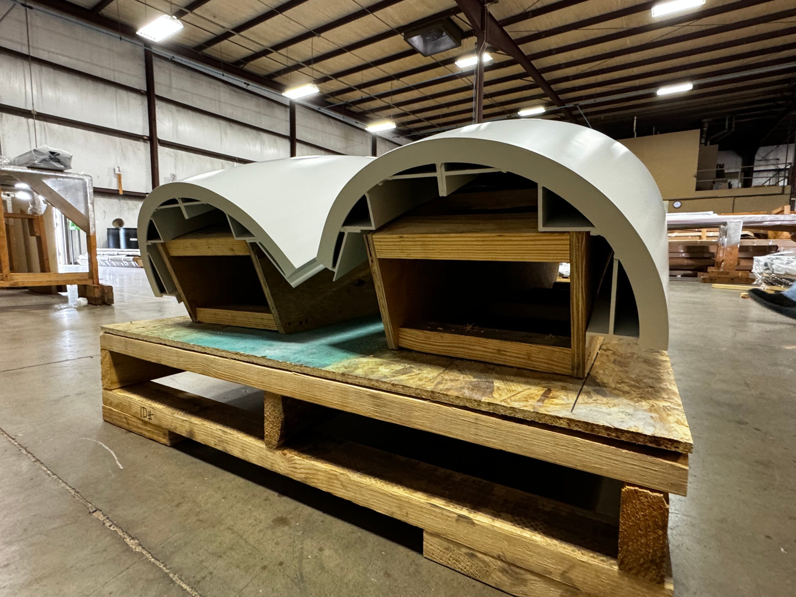 Two large curved aluminum canopy sections on a shop pallet, ready to ship