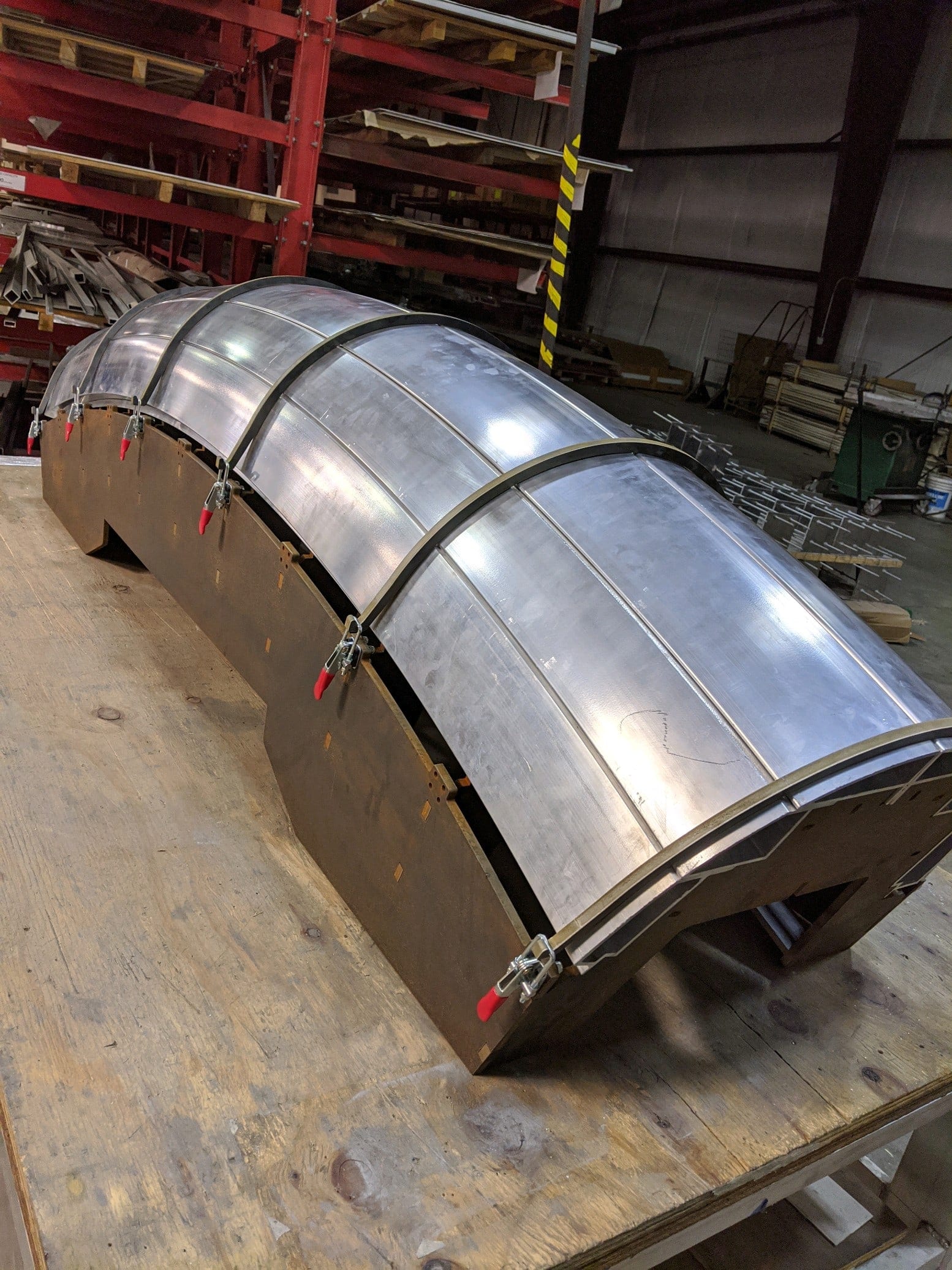 Curved aluminum canopy component clamped to a forming fixture