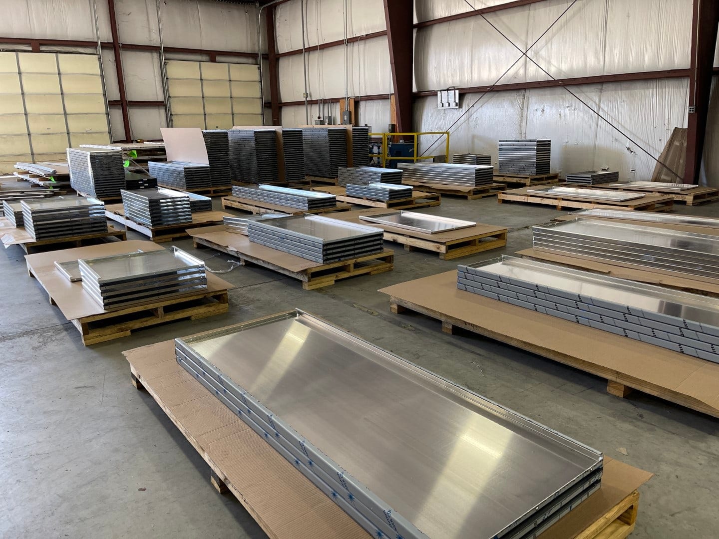 Stacks of finished brake-formed aluminum valance panels on pallets in the shop
