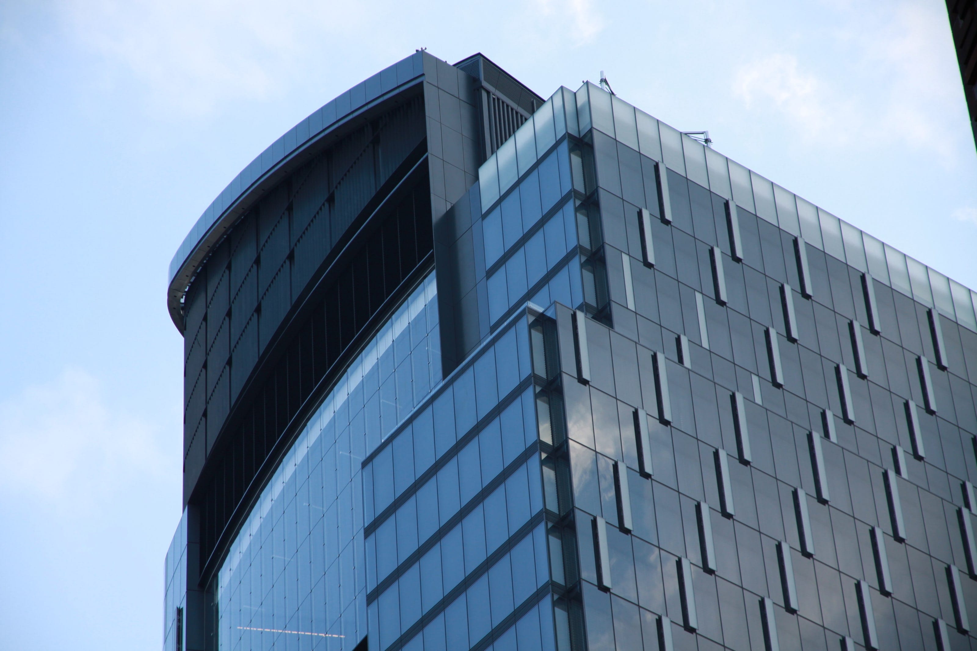 Office building with a curved façade of dark glass and painted metal panels