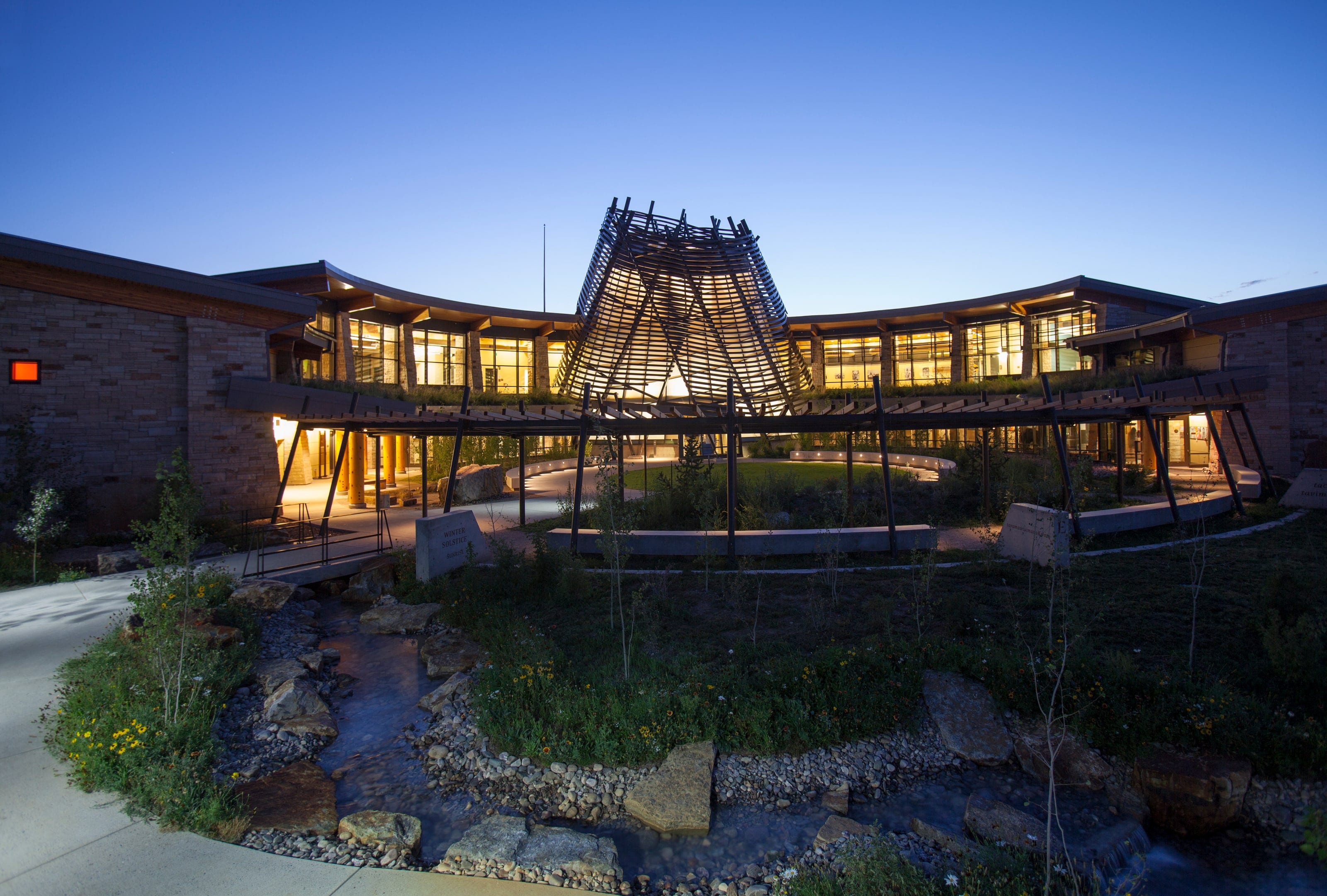 Southern Ute Cultural Center lit at dusk, its sunshade tower above the stream garden