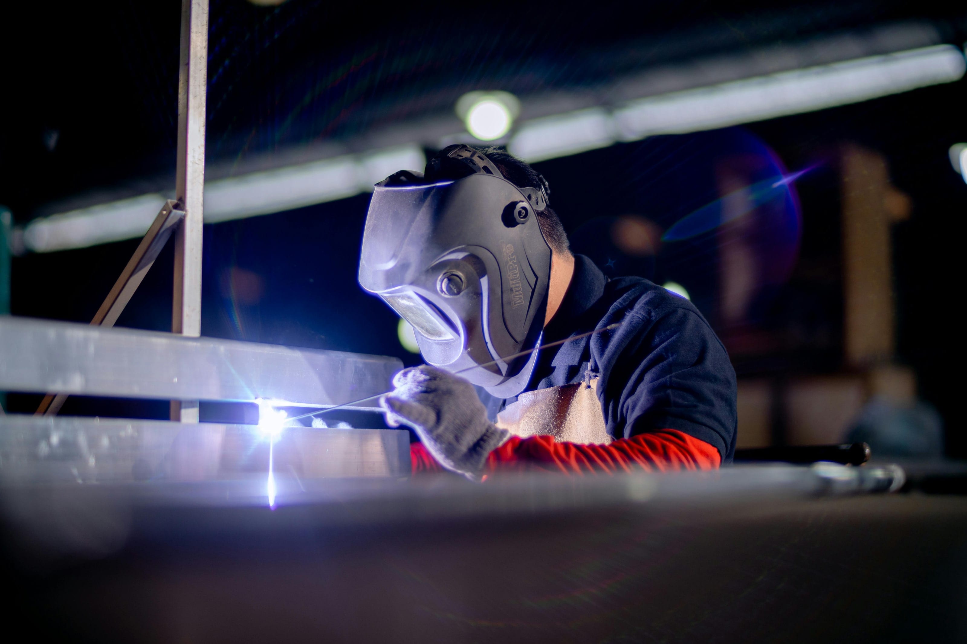 Mid-Am welder in a welding helmet TIG welding at the bench